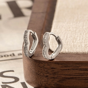 Silver heart-shaped hoop earrings with zircon accents on a rustic vintage background