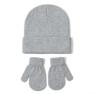 Close-up of grey knitted winter hat and matching mittens set on white background
