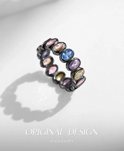 Macro view of black metal ring with multi-colored oval cut gems in bezel setting