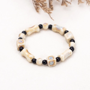 Keramikknochen-Armband im New Chinese Style mit schwarzen Perlen auf beige Stoffuntergrund
