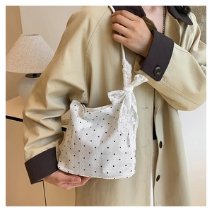 Detail view of white cotton bucket bag with black polka dots and lace bow decoration