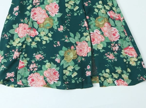 Detail of dark green floral midi skirt featuring vintage rose prints and side slit
