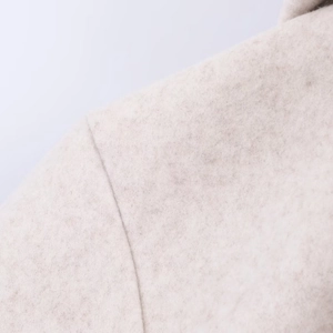 Macro shot of soft oatmeal wool fabric texture and neat stitching on a hooded coat