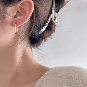 Close-up of minimalist gold geometric hoop earrings worn by a model for size and style