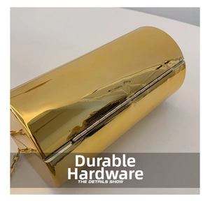 Detailed macro view of the glossy gold cylindrical clutch bag and fine metal chain strap
