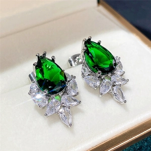 Macro detail of pear-cut emerald green gemstone earring set in silver with zircon