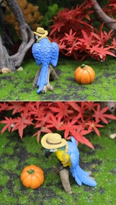 Macro shot of resin macaw figurines with straw hats and mini pumpkins for autumn decor