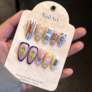 Detail of 3D lemon and blue fish nail art on long stiletto press-on nails with floral motifs