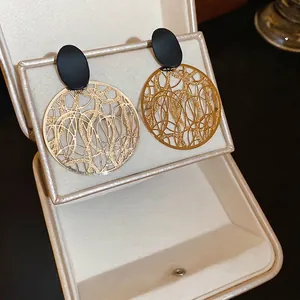 Retro hohle Metall-Ohrringe mit schwarzen ovalen Steckern in einer Schmuckbox