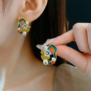 Detail of vintage flower earrings with pearls and colorful enamel on a gold frame