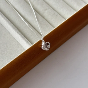 Detail shot of 18k gold plated hollow square necklace on grey jewelry display tray