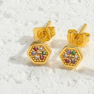 Macro detail of hexagonal gold earrings with vibrant colorful cubic zirconia inlay
