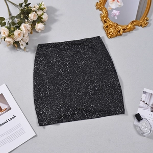 Flat lay of black mini skirt with white splatter dots next to vintage mirror and roses