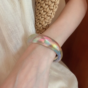 Close-up of iridescent acrylic geometric bracelet on wrist with summer fashion aesthetic