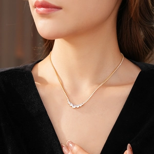 Detail of gold necklace featuring round and marquise-cut cubic zirconia on a model