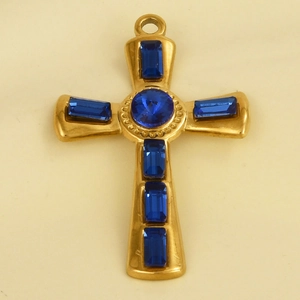 Close-up of golden cross pendant with sparkling blue rectangular and round crystals