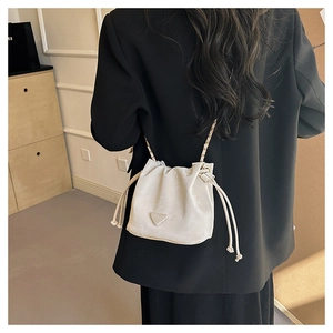Detail of white drawstring bucket bag with chain strap shown on black blazer outfit
