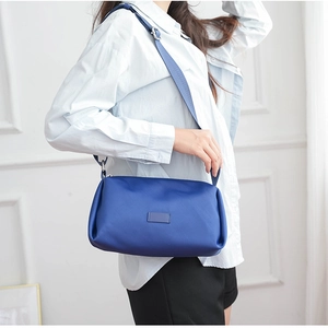 Bolso bandolera de nailon azul con correa ancha ajustable en un modelo femenino