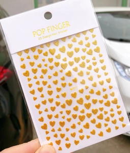Detail of Me017 3D nail stickers featuring golden glitter heart designs in retail packaging