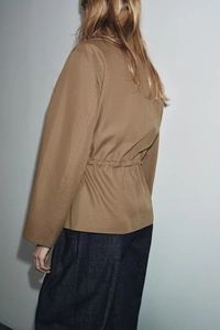 Detail view of the back drawstring waist and structured fabric of the camel parka jacket