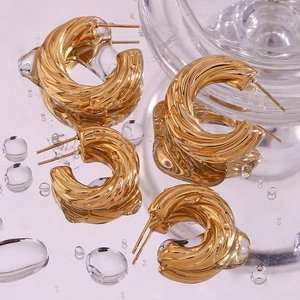 Macro detail of 18K gold-plated twisted hollow hoop earrings with metallic texture