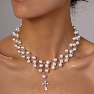 Détail d'un collier de perles multicouche avec un pendentif croix serti de zircons