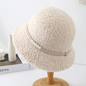 Détail d'un chapeau cloche beige en polaire bouclée avec perles décoratives et texture douce