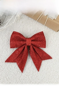 Macro detail of Christmas bow with red sequins and glitter on soft white faux fur