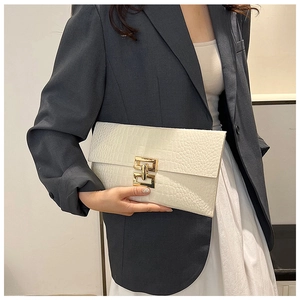 Gros plan d'une pochette enveloppe blanche à motif crocodile avec boucle dorée