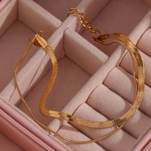 Macro shot of double-layer gold snake and link chain bracelet in a pink velvet jewelry box