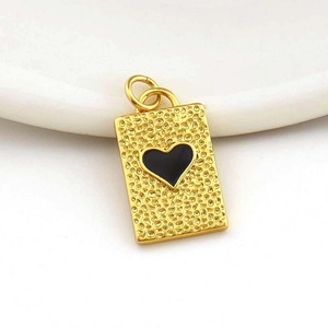 Macro shot of 18k gold plated heart pendant with black enamel on white ceramic tray