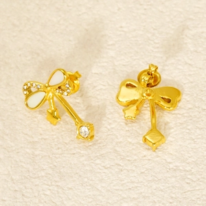 Macro detail of bow earrings featuring white enamel, small crystals, and square zircon drop