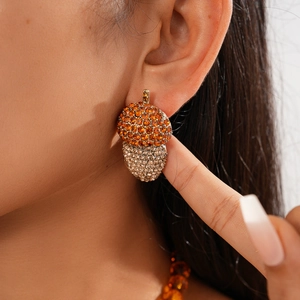 Close-up of sparkling crystal acorn drop earrings with orange and gold rhinestones