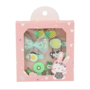 Detail der rosa Geschenkbox mit pastellfarbenen Frucht- und Bogen-Haarspangen