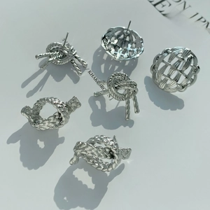 Detailed view of silver knot stud earrings set with intricate woven metal textures