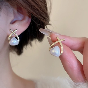 Detail of elegant gold cross frame earrings with teardrop pearl drops for women