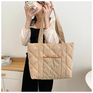 Quilted beige nylon tote bag with front pocket shown on a model for casual daily use