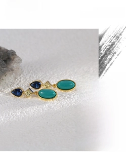 Detail showing elegant triple stone gold earrings with blue zircon and turquoise drop design