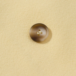 Close-up of a brown resin button with double-breasted style on wool coat fabric