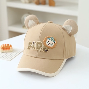 Détail d'une casquette bébé avec oreilles 3D et écusson lion en coton beige confortable