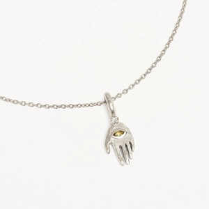 Macro detail of Hamsa Hand pendant with yellow eye and cubic zirconia on silver chain