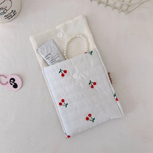Detailed macro view of quilted cherry print cotton bag with snap button and white piping