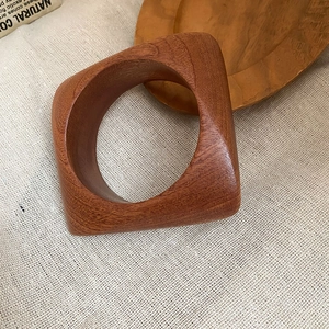 Détail du bracelet géométrique en bois brun-rouge avec texture veinée naturelle