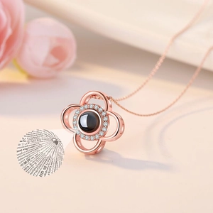 Detail of rose gold clover necklace with black stone showing 100 languages projection