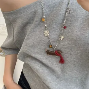 Détail du collier pendentif teckel avec écharpe rouge et perles colorées en style superposé