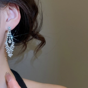 Close-up of elegant long geometric earrings with sparkling rhinestones worn by a model