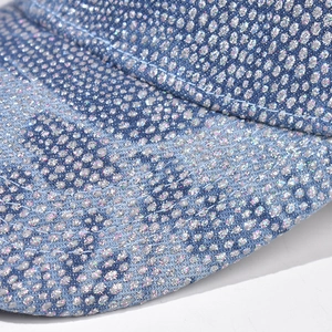 Macro detail of sparkling rhinestones on light blue denim baseball cap fabric