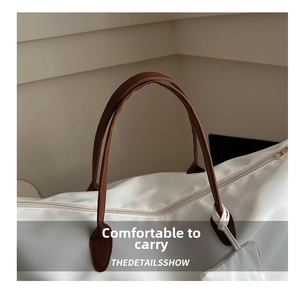 Detail of comfortable brown faux leather handles and sturdy stitching on white oxford tote bag