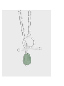 Macro shot of silver necklace chain featuring green gemstone pendant and OT clasp detail