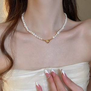 Detail of 18K gold heart pendant on baroque freshwater pearl necklace worn by a model